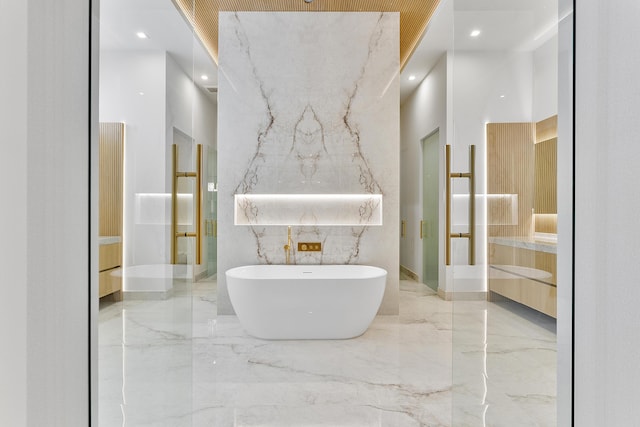 full bathroom with stone wall, a freestanding tub, vanity, marble finish floor, and walk in shower