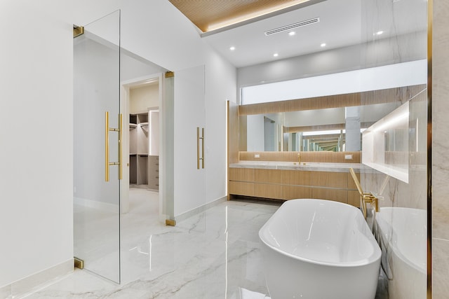 bathroom with visible vents, a soaking tub, marble finish floor, a walk in closet, and vanity