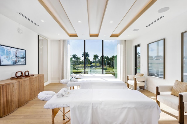 bedroom with light wood-style floors, visible vents, and floor to ceiling windows