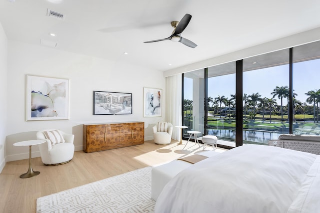 bedroom featuring wood finished floors, visible vents, baseboards, access to outside, and a wall of windows