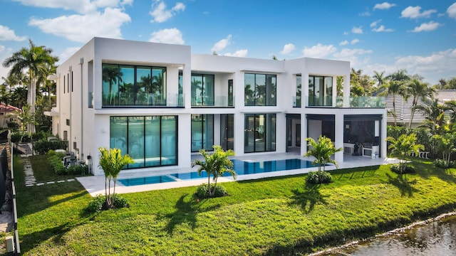 rear view of property featuring stucco siding, a water view, a lawn, a patio area, and a balcony