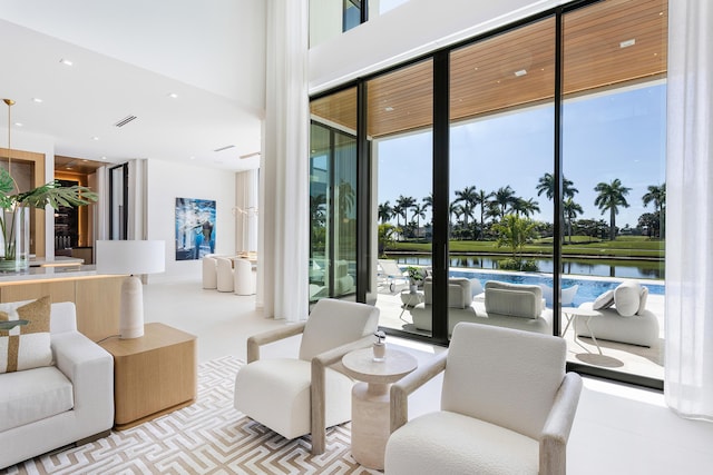 interior space featuring a high ceiling, a wall of windows, a water view, and visible vents