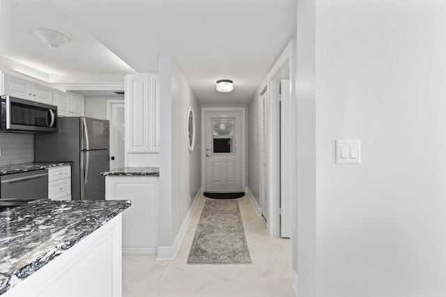 kitchen with appliances with stainless steel finishes, dark stone counters, decorative backsplash, and white cabinets