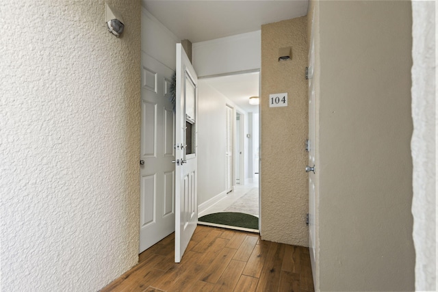 hall with wood finished floors and a textured wall