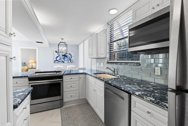 kitchen featuring white cabinetry, appliances with stainless steel finishes, backsplash, and dark stone counters