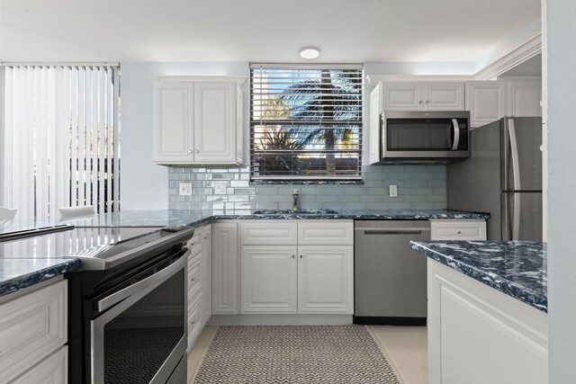 kitchen featuring stainless steel appliances, white cabinets, a kitchen bar, and kitchen peninsula