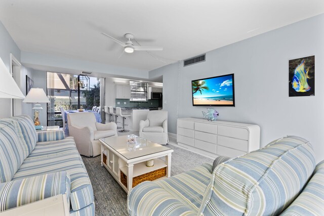 living room with ceiling fan and a wall of windows