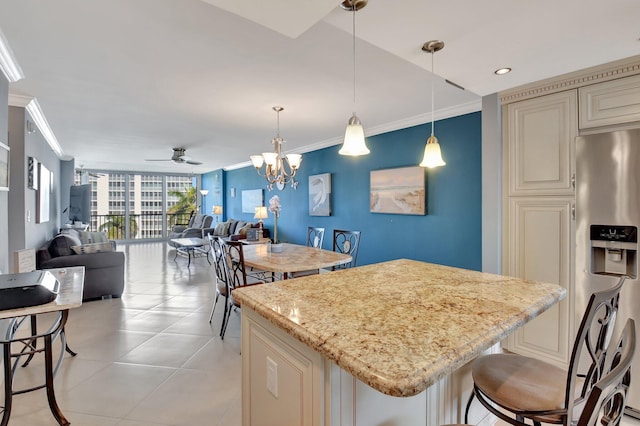 kitchen featuring stainless steel refrigerator with ice dispenser, crown molding, a center island, hanging light fixtures, and cream cabinetry