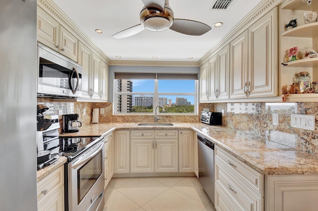 kitchen with sink, light tile patterned floors, light stone counters, stainless steel appliances, and cream cabinetry