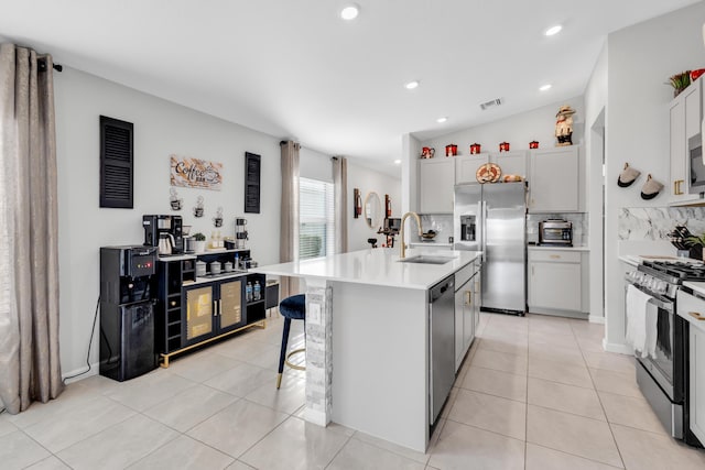 kitchen featuring sink, a breakfast bar area, white cabinetry, an island with sink, and stainless steel appliances