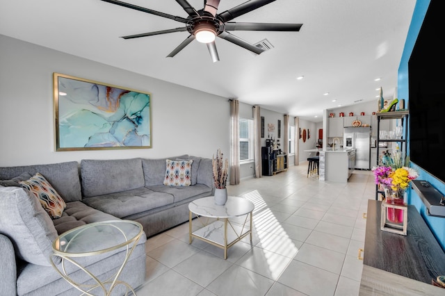 living room featuring light tile patterned floors, sink, and ceiling fan