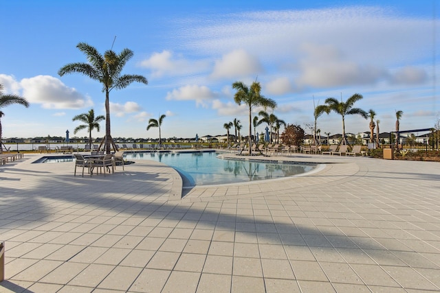 view of swimming pool featuring a water view and a patio area