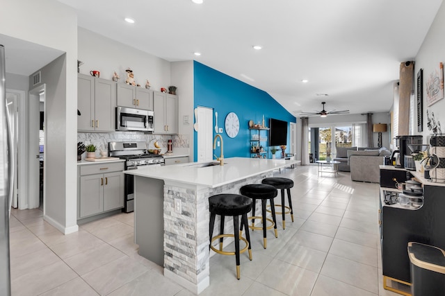 kitchen featuring gray cabinets, an island with sink, appliances with stainless steel finishes, and sink