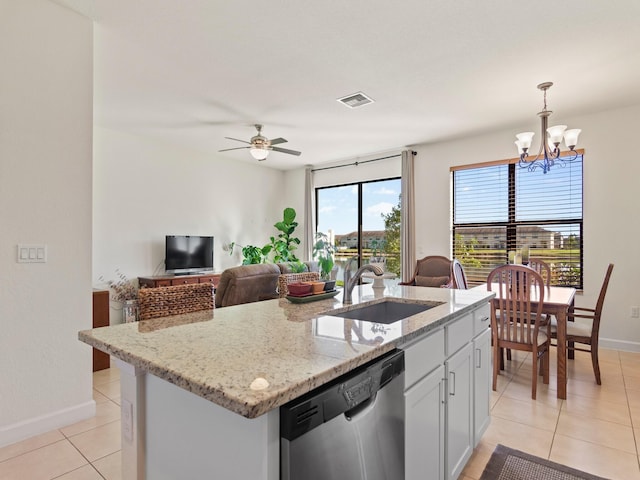 kitchen featuring pendant lighting, dishwasher, sink, light stone countertops, and a center island with sink