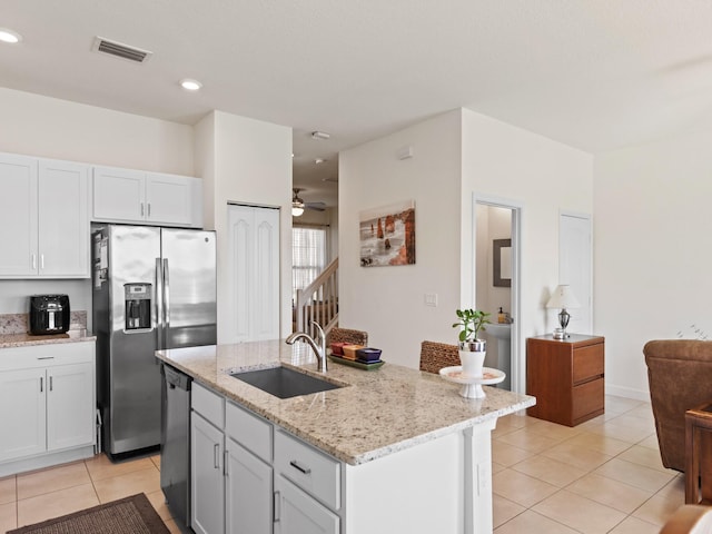 kitchen featuring sink, appliances with stainless steel finishes, an island with sink, light stone countertops, and white cabinets