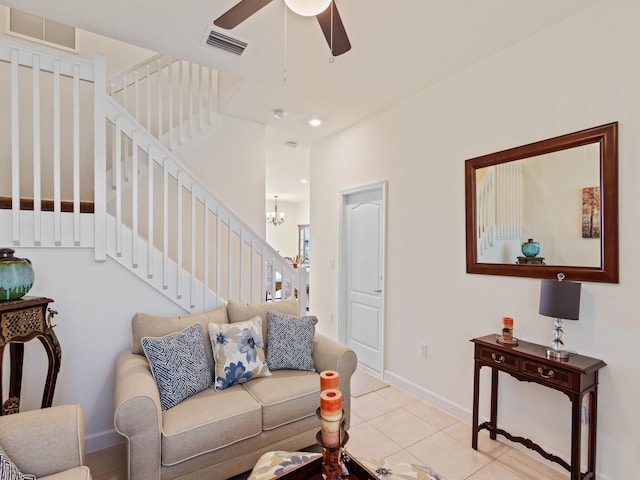 tiled living room with ceiling fan with notable chandelier