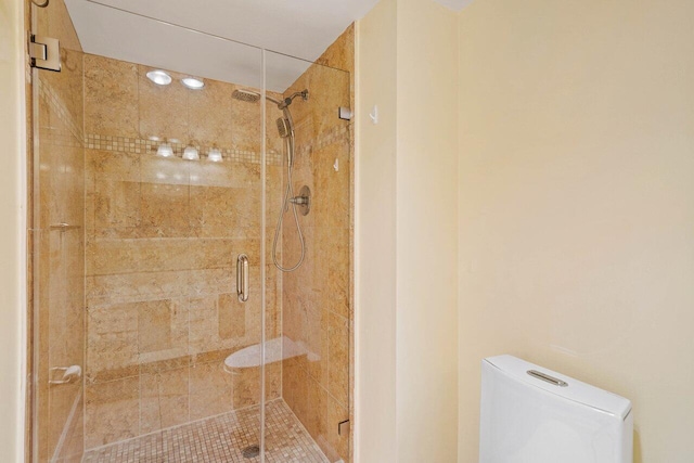 bathroom with a shower with shower door and toilet