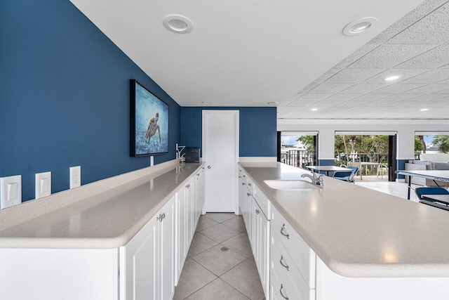 kitchen with white cabinetry, sink, light tile patterned floors, and kitchen peninsula