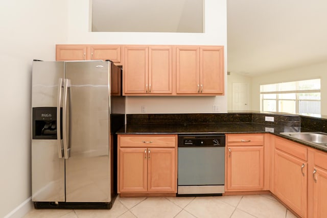 kitchen with light tile patterned flooring, stainless steel appliances, sink, and dark stone counters