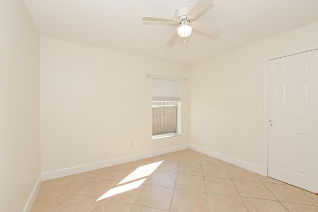 tiled empty room with ceiling fan and a textured ceiling