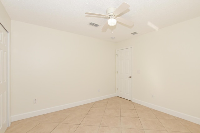 tiled empty room with ceiling fan and a textured ceiling