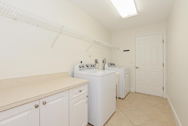 laundry room with cabinets, washer and dryer, and light tile patterned floors