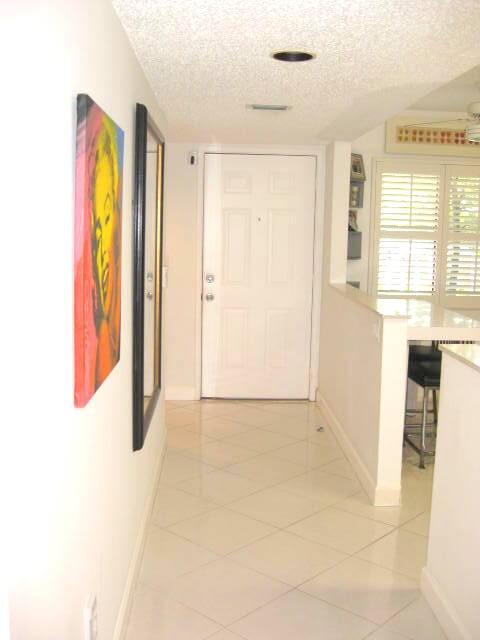 hallway with a textured ceiling and light tile patterned flooring