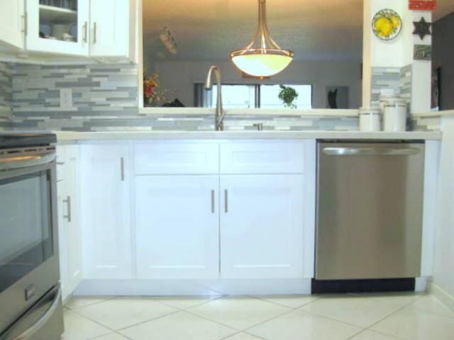 kitchen featuring light tile patterned flooring, sink, white cabinets, stainless steel appliances, and backsplash