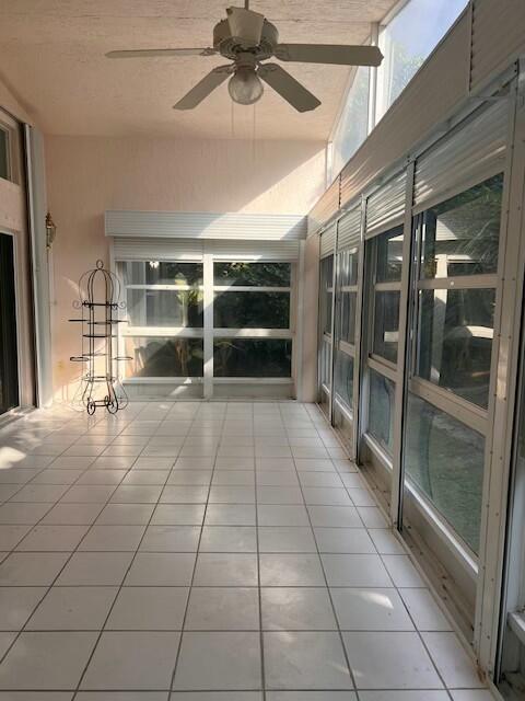 unfurnished sunroom featuring ceiling fan