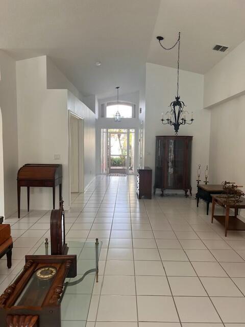 hallway featuring light tile patterned flooring, high vaulted ceiling, and a chandelier