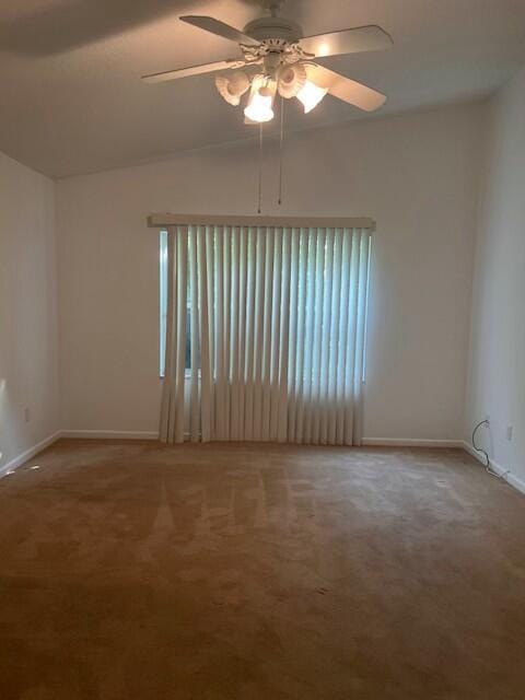 empty room with vaulted ceiling, ceiling fan, and carpet flooring