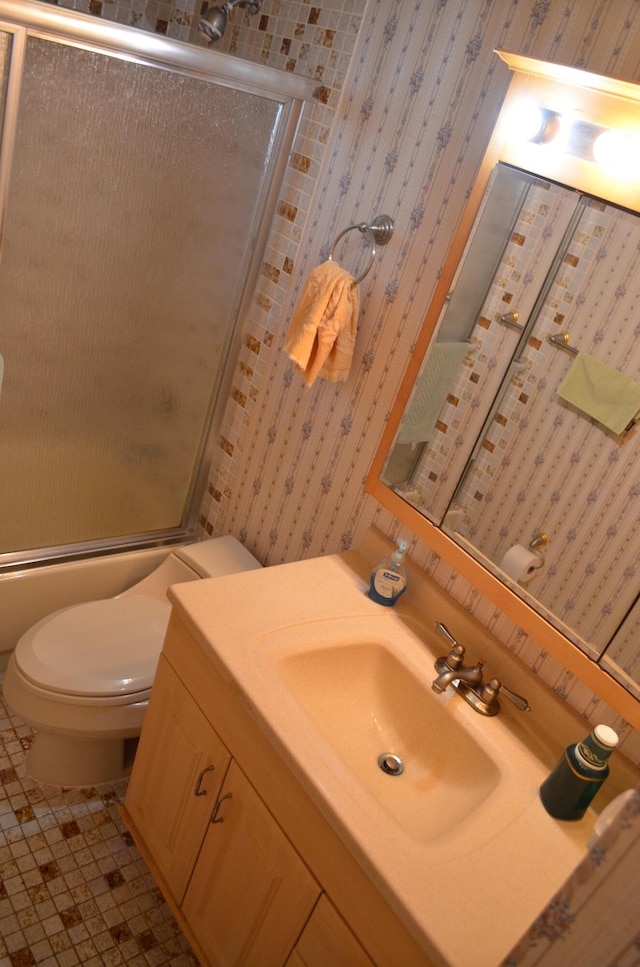 full bathroom with toilet, tile patterned floors, vanity, and bath / shower combo with glass door