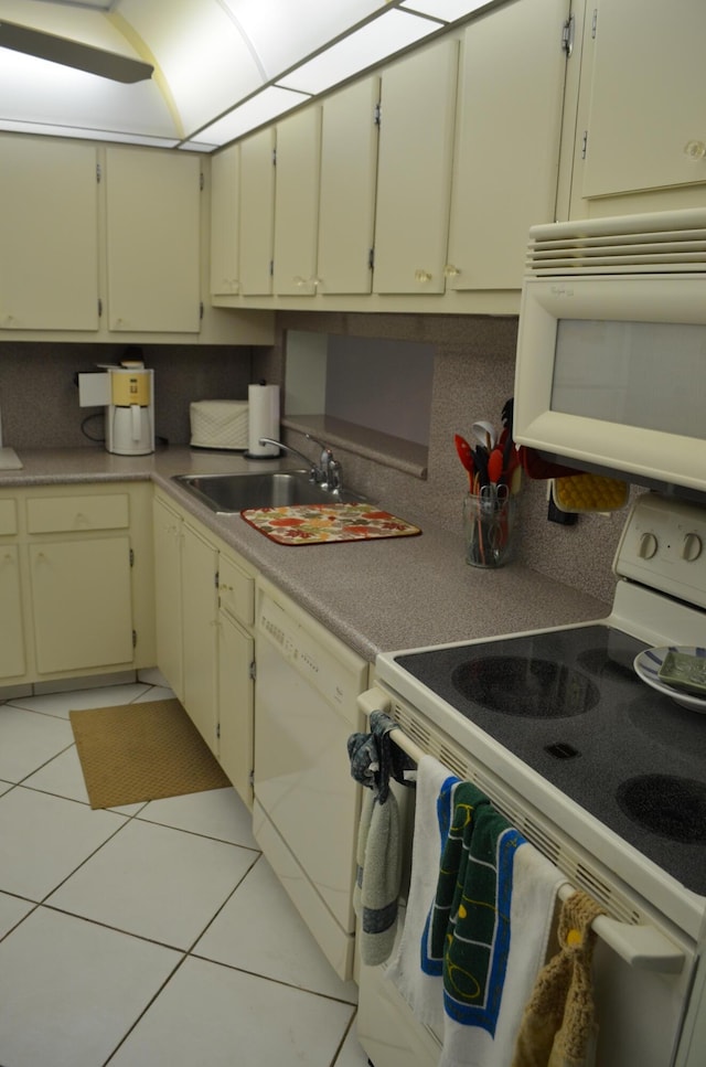 kitchen featuring sink, light tile patterned floors, white appliances, cream cabinets, and backsplash