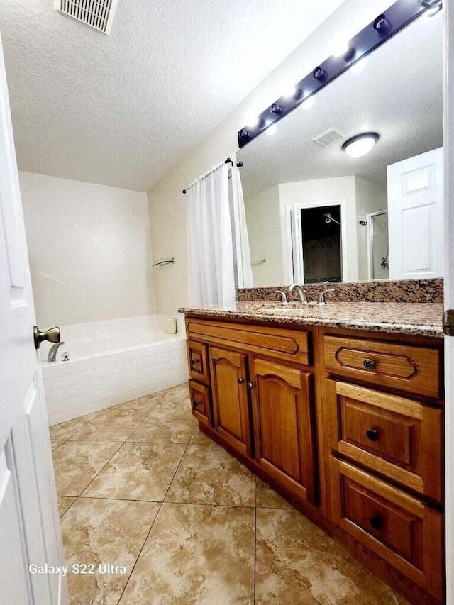 bathroom with vanity, tile patterned floors, independent shower and bath, and a textured ceiling