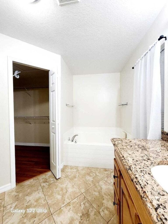 bathroom featuring vanity, tile patterned flooring, a textured ceiling, and a washtub