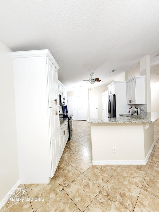 kitchen featuring ceiling fan, white cabinetry, light stone countertops, black appliances, and kitchen peninsula