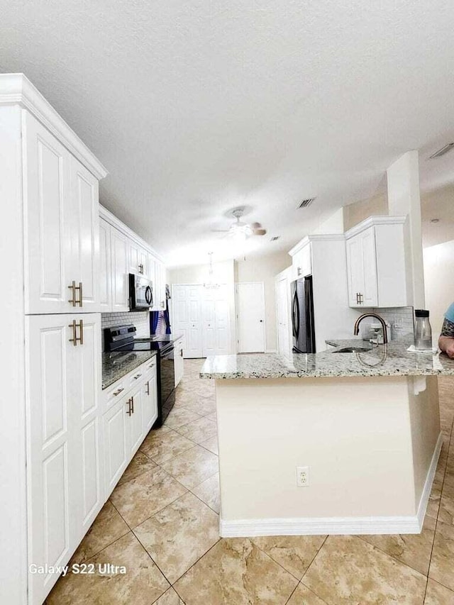 kitchen featuring sink, refrigerator, black electric range, light stone countertops, and white cabinets