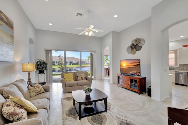 living room featuring ceiling fan, light tile patterned floors, and a high ceiling