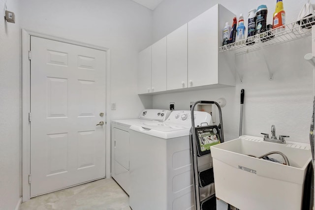 washroom featuring cabinets, washing machine and clothes dryer, and sink