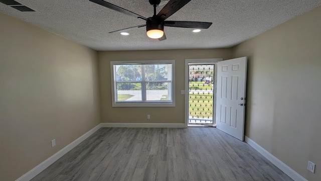 empty room featuring ceiling fan, a textured ceiling, and light wood-type flooring