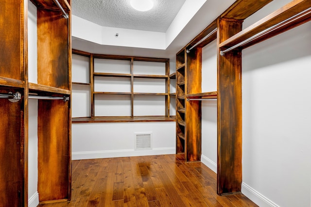 walk in closet with dark wood-type flooring