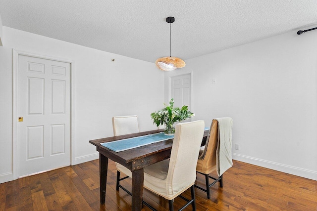 dining space featuring dark wood-type flooring and a textured ceiling