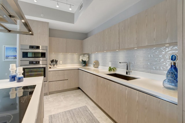 kitchen featuring sink, tasteful backsplash, light brown cabinets, track lighting, and double oven