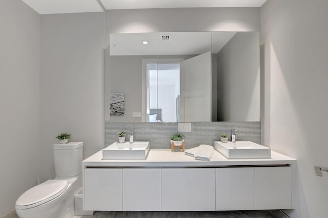 bathroom featuring tasteful backsplash, vanity, and toilet