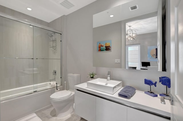 full bathroom with a notable chandelier, enclosed tub / shower combo, vanity, and toilet