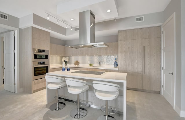 kitchen featuring tasteful backsplash, island range hood, a kitchen bar, and a kitchen island