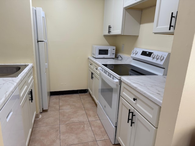 kitchen with light stone countertops, light tile patterned floors, white cabinets, and white appliances