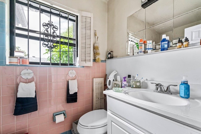 bathroom with vanity, toilet, and tile walls