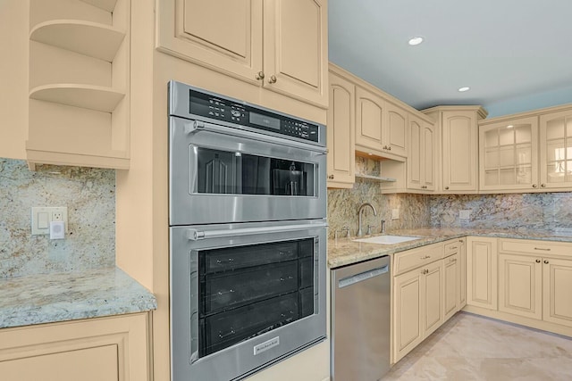 kitchen featuring appliances with stainless steel finishes, light stone countertops, sink, and decorative backsplash