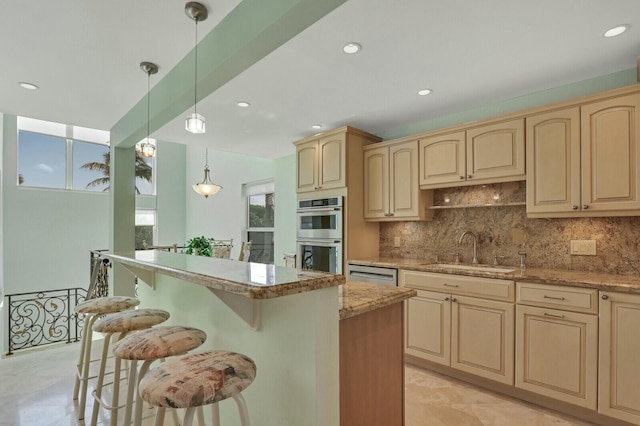 kitchen with sink, appliances with stainless steel finishes, hanging light fixtures, a kitchen breakfast bar, and light stone counters